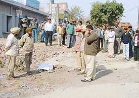 Police officials examine the site near Indian Overseas Bank, Transport Nagar, in Ludhiana, where the body of a migrant was found on Saturday. 