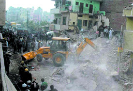 A bulldozer removing the debris of a building collapsed at Pandav Nagar in the Capital on Tuesday