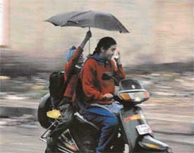 A child going to school tries to shield himself from getting drenched in Ludhiana on Tuesday morning