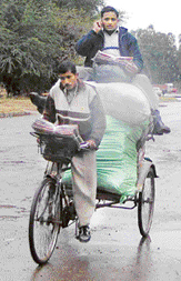 A man sitting atop his goods in a rickshaw makes most of his 'free' time, by either calling a client or his family, in Phase VI of Mohali on Wednesday. 