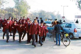 After being deserted by their bus driver, students cross the busy BRS Nagar-Sarabha Nagar road in Ludhiana on Friday