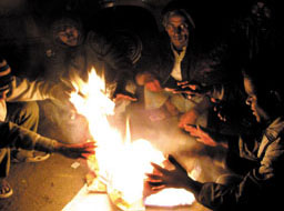 Workers warming their hands to beat the cold wave in the Capital on Sunday