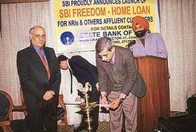 Mr A. Krishan Kumar, General Manager, SBI, lights a lamp at the launch of the home loan. Mr Akhilesh Mohan, DGM, is standing next to him