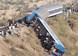 Army troops and railway workers gather around a derailed passenger train in Domeli, about 100 km southeast of Islamabad, on Monday.