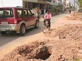 A cyclist avoids a pit dug up by a private telecom company to lay cables in the Modern Housing Complex of Mani Majra