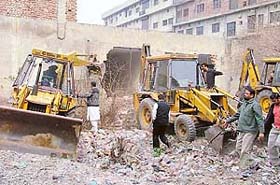 Councillor Rajesh Jain argues with the driver of the bulldozer as it advances to pull down the outer wall of a hosiery building in Ludhiana