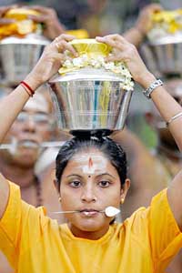 A woman devotee carries a ritualistic pot of milk on her head while walking towards the Sri Maha Mariamman temple in Batu Caves, Kuala Lumpur