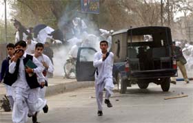 Pakistani students run after police fired teargas at a protest rally in Peshawar