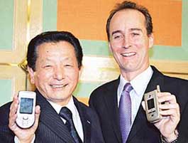 Japanese electronics giant Sanyo Executive Takenori Ugari (left) shows a Nokia mobile phone while Nokia Japan President Tyler McGee shows a Sanyo handset as they announced the companies would form a global joint venture to develop and produce third-generation (3G) mobile phones, at a Tokyo hotel on Tuesday.