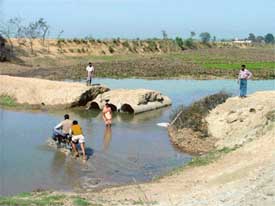 Villagers wade through the Jassowal drain, close to the damaged bridge