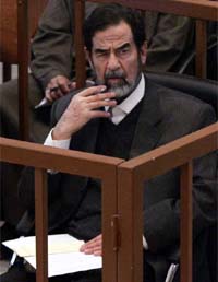 Former Iraqi President Saddam Hussein listens to one of the prosecutors in Baghdad