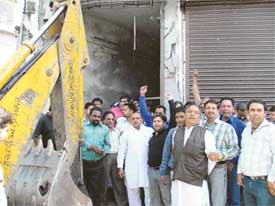 Congress councillors and their supporters prevent a JCB machine from demolishing an illegal structure at Ghumar Mandi in Ludhiana on Thursday
