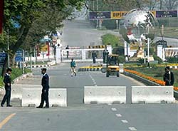 Pakistani police officers stand guard near concrete blocks used to close a road leading to the US Embassy before President Bush's visit to Islamabad on Friday. 