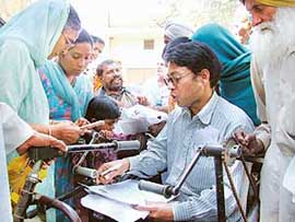 Raj Kumar, a physically challenged, fills forms of pension seekers at a camp held in Bathinda on Saturday.