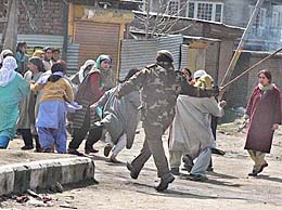 A policeman chases a group of women protesters in the Tangpora locality of Batmaloo in central Srinagar on Sunday.