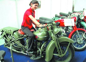 A woman tries her hand on a vintage bike during an auto show organised by the Delhi Scooter Traders Association at Talkatora Stadium in the Capital on Friday
