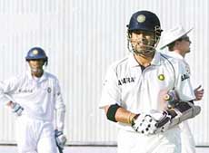 Sachin Tendulkar walks back to the pavilion after being dismissal by Englands Andrew Flintoff as Indian captain Rahul Dravid looks on during the third day of the second Test at the Punjab Cricket Association Stadium in Mohali on Saturday. 