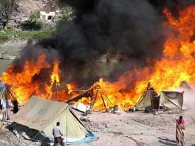 Pakistani earthquake survivors stand helpless as fire destroys their tents in a makeshift camp in Muzaffarabad on Saturday. 