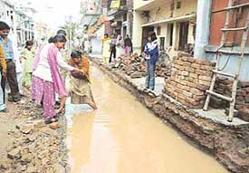 Ms Kamlesh, former Mayor, helps a resident out of a trench full of water at Ram Darbar, Chandigarh, on Tuesday.