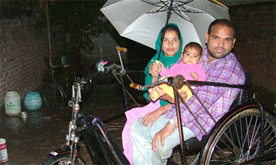 Bir Chand, with his wife and daughter, on a tricycle in Nangal Karar Khan village near Jalandhar on Tuesday