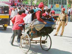 A policeman watches helplessly as an overloaded rickshaw ferries schoolchildren in Ludhiana on Friday