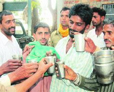 Devotees partake of liquor prasad at the samadh of Baba Rode in Bhoma village. 