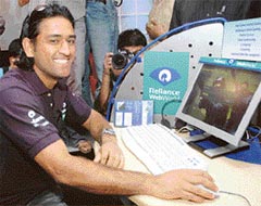 Dhoni to bat for ADAG: Cricketer Mahendra Singh Dhoni is watched by media representatives as he uses a computer in Mumbai on Thursday after being announced a brand ambassador for the Reliance-Anil Dhirubhai Ambani Group (ADAG). Dhoni will endorse the companys products and service. Coinciding with the event, the company also launched Dhoni Zone and Dhoni Magic on R-World, the Reliance India mobile portal.