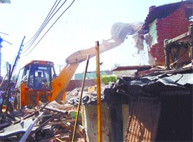 An MCD bulldozer demolishing a slum cluster near Pragati Maidan in the Capital on Wednesday