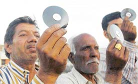 Residents look at the eclipsed sun through dark screens in Ludhiana on Wednesday