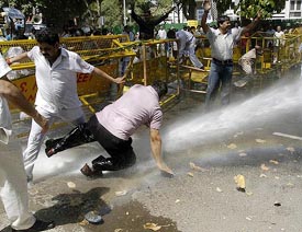Workers of the Delhi Pradesh Congress try to avoid the water cannon during a demonstration near the residence of BJP MP Vijay Kumar Malhotra in New Delhi on Wednesday when they were demanding the resignation of the BJP leader on the office of profit issue.
