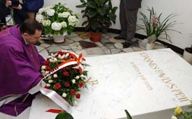 A priest lays flowers on the tomb of the late Pope John Paul II during a special service held at the grotto of St Peter's Basilica in the Vatican on Sunday