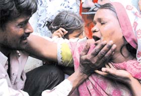 A woman being consoled by her brother after the devastation caused by the fire at Yamuna Pushta