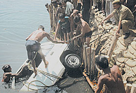 Officials of the Delhi Fire Service with the help of local people try to pull out a car from the Yamuna in the Capital on Friday.