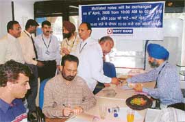 Officials of HDFC Bank Ltd and the Reserve Bank of India exchange soiled and mutilated currency notes with new ones in Chandigarh on Saturday.