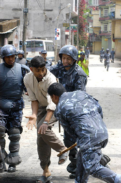 Riot police baton charge a political activist during the day-time curfew in Kathmandu on Sunday