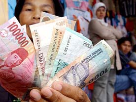 An Indonesian vendor holds Rupiah notes at a textile market in Jakarta on Sunday. Indonesian President Susilo Bambang Yudhoyono called for an Asia-Pacific economic partnership to boost investments and empower small and medium businesses.