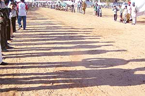 A setting sun casts elongated shadows as people assemble for a public event in Balongi village near Mohali.