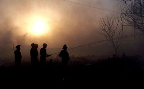 Delhi Fire Service jawans try to control the fire at Vasant Kunj Jhuggi Basti, in the Capital.