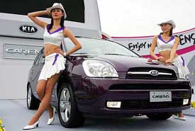 Models pose next to Kia Motors Corps New Carens at its unveiling in South Korea on Thursday