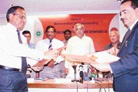 IOC Director B.M. Bansal and HSIDC MD Rajiv Arora exchange documents after signing an MoU to develop Panipat as a petrochemical hub as Haryana Chief Minister Bhupinder Singh Hooda looks on.
