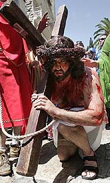 A pilgrim plays the part of Jesus Christ, complete with a crown of thorns and actors blood, carries a cross on the way along the Via Dolorsa towards the Church of the Holy Sepulchre during the Good Friday procession in Jerusalems Old City on Friday