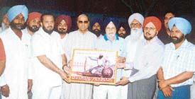 Mr Krishan Kumar Bawa honours Mr Kuljit Singh Sidhu, IAS (retd), at Raqba village in Ludhiana district on Wednesday. 