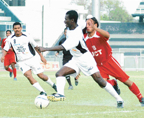 Baldeep Singh of JCT Mills rushes to tackle Yusif Yakubu of Mahindra United as Jose Barreto looks on, in the tenth National Football League at Ludhiana's Guru Nanak Stadium on Saturday. Mahindra United won the match 1-0.