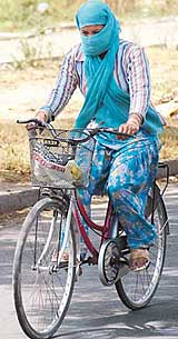 A cyclist wraps her chunni around face and head to protect herself against rising temperature in Chandigarh.