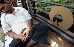 A vendor takes a nap next to a Reliance logo in Mumbai on Thursday.