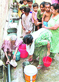 Jalandhar residents collect water from a pipe running over a drain
