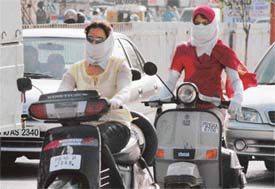 Girls cover their faces to protect themselves from heat and rising temperature in Ludhiana on Friday