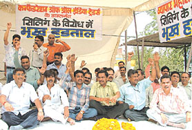 Traders sit on a hunger strike to protest against the MCDs sealing drive, at Dabri Chowk in the Capital on Sunday.