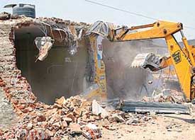 A structure being pulled down during a demolition drive near Daria village
