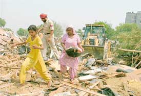 Slum-dwellers move their belongings to safer places as a demolition drive is in progress in Ludhiana on Wednesday